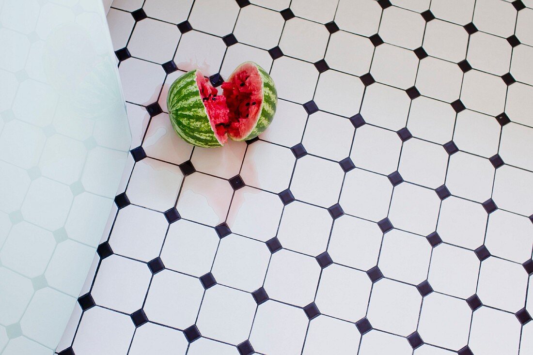 A watermelon on the floor of a kitchen