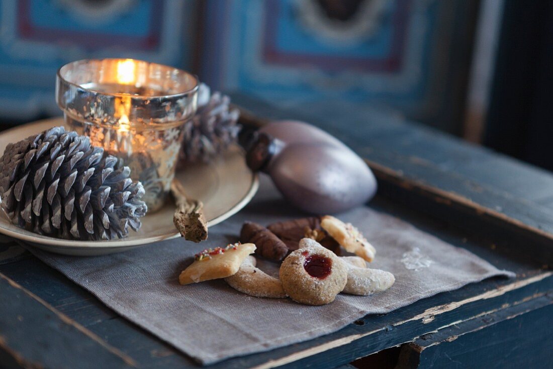 Biscuits next to a plate decorated for Christmas with a tealight and pine cones