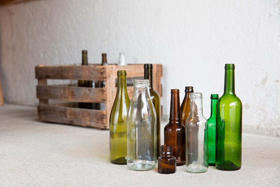 Various empty bottles in front of a wooden crate in a garage