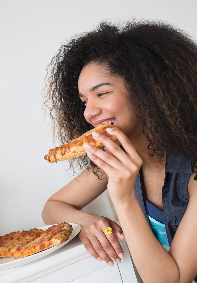 A teenager eating pizza