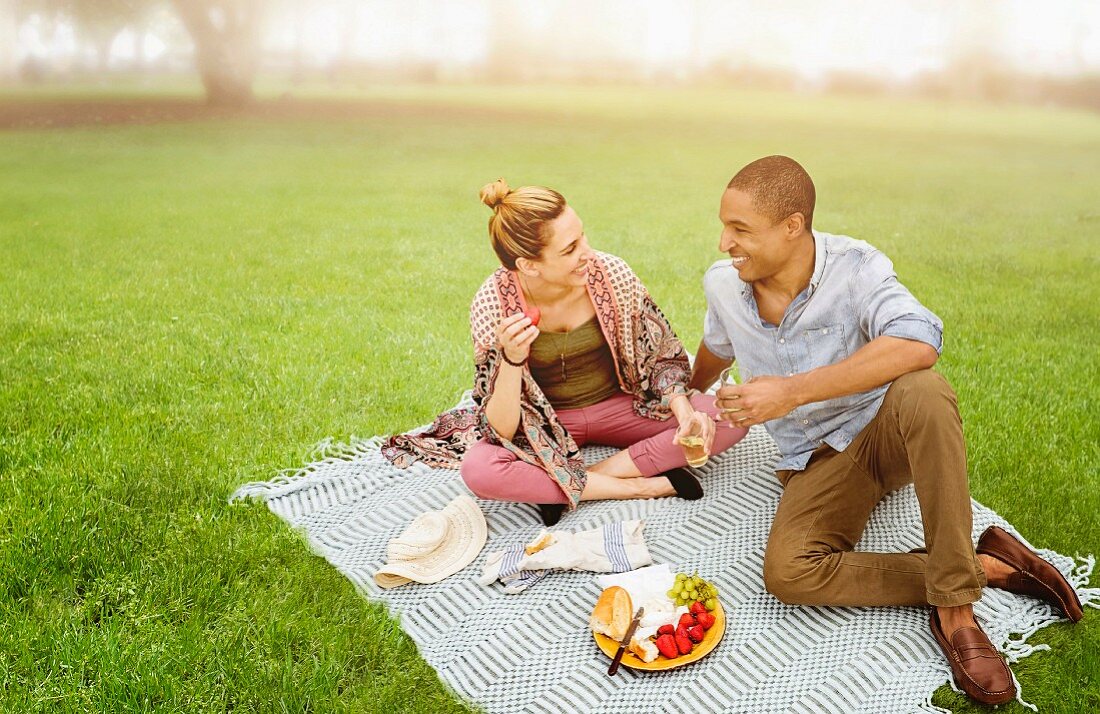 Pärchen macht Picknick auf Wiese im Park