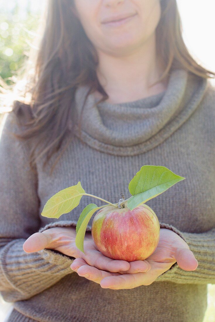 A woman holding a freshly plucked apple