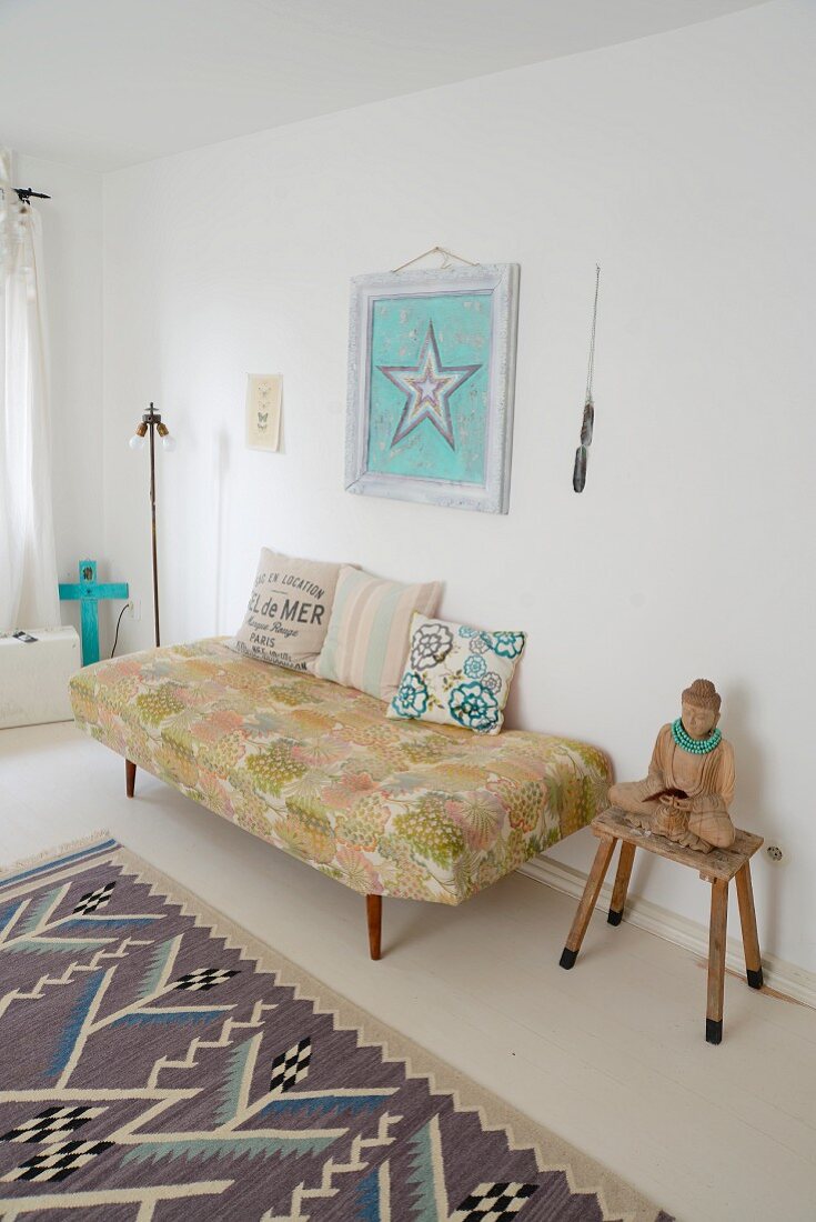 Buddha statue on stool next to 60s-style couch below picture of star on wall