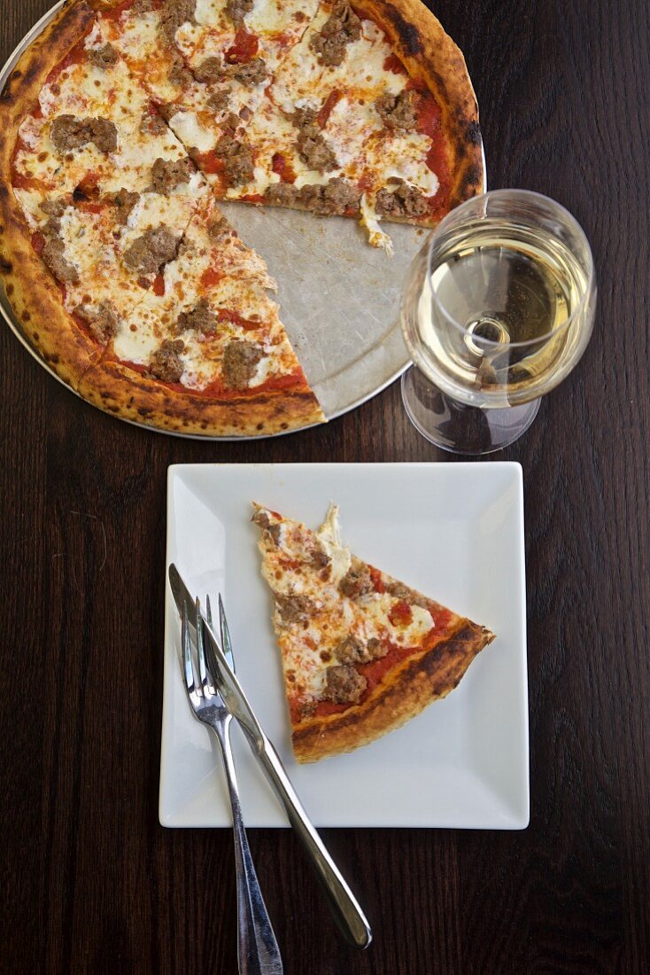 Pizza mit Salsiccia, dazu Weißwein