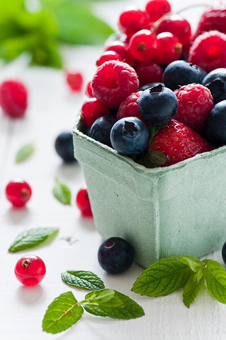 Fresh berries berries and fresh mint leaves in a cardboard punnet