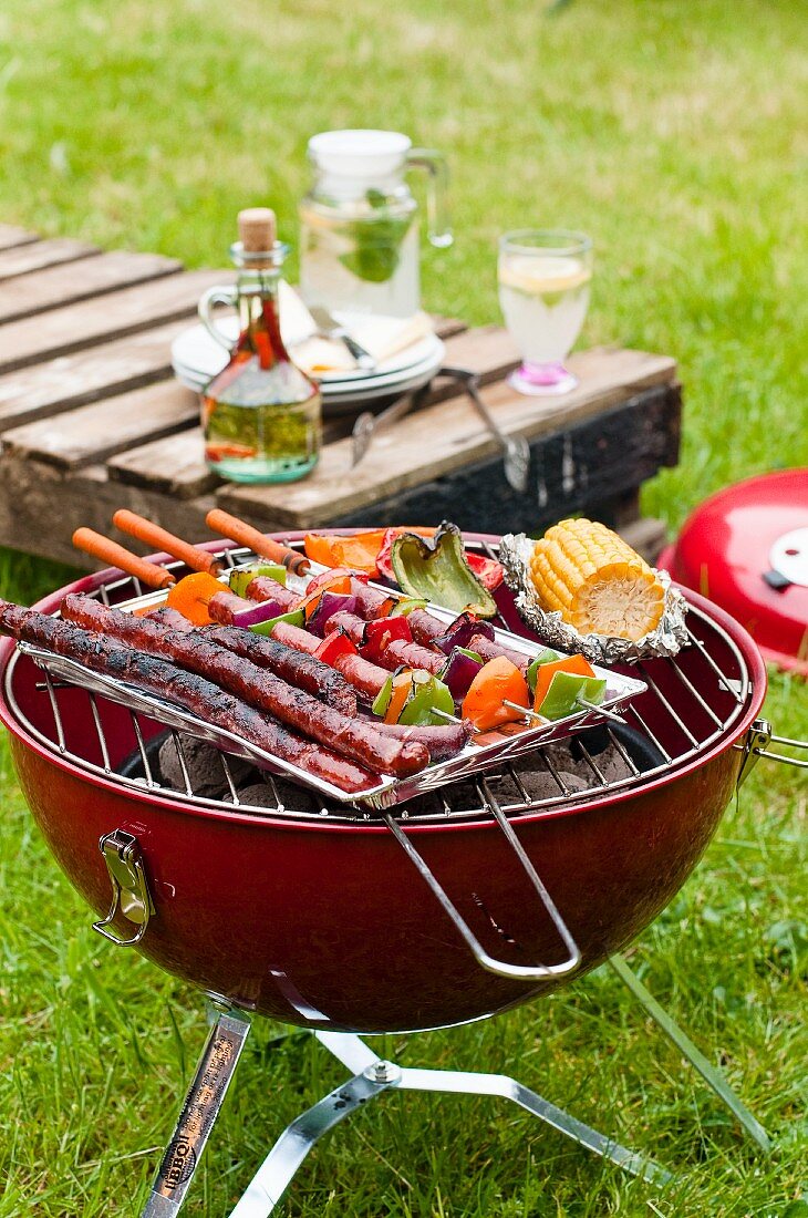 Sausages and vegetables on a charcoal barbecue