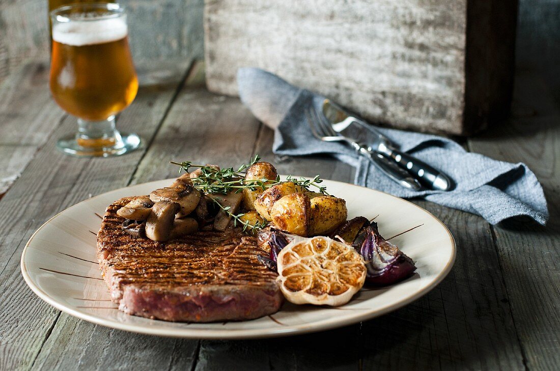 Grilled rib eye steak with red onions, garlic, mushrooms and thyme potatoes