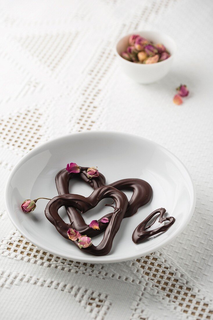 Schokoladenherzen mit getrockneten Rosenblüten auf einem Teller