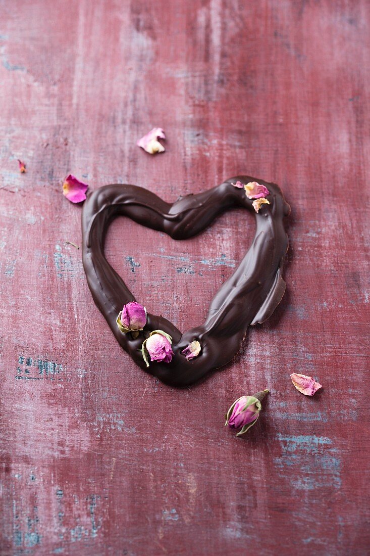 Schokoladenherz mit getrockneten Rosenblüten