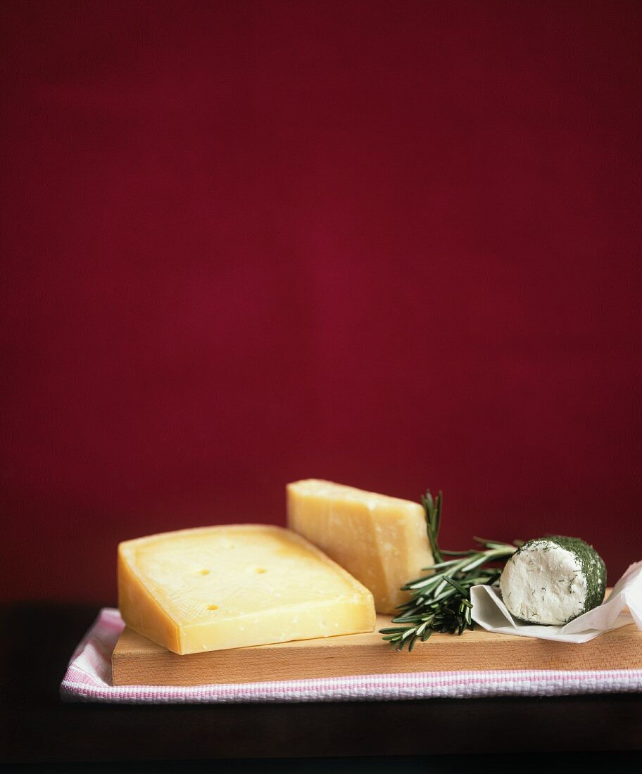 Various types of cheese and rosemary on a chopping board