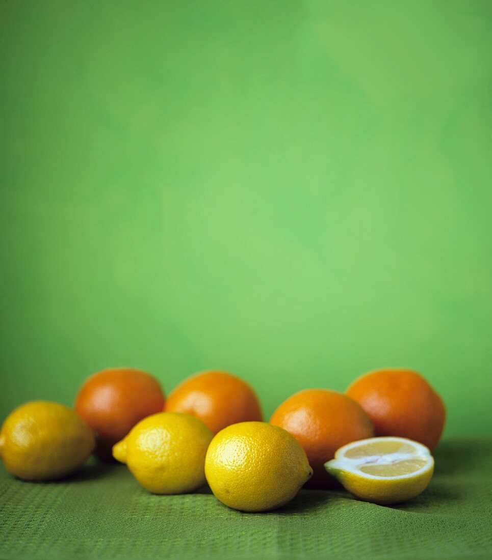 Lemons and oranges on a green surface
