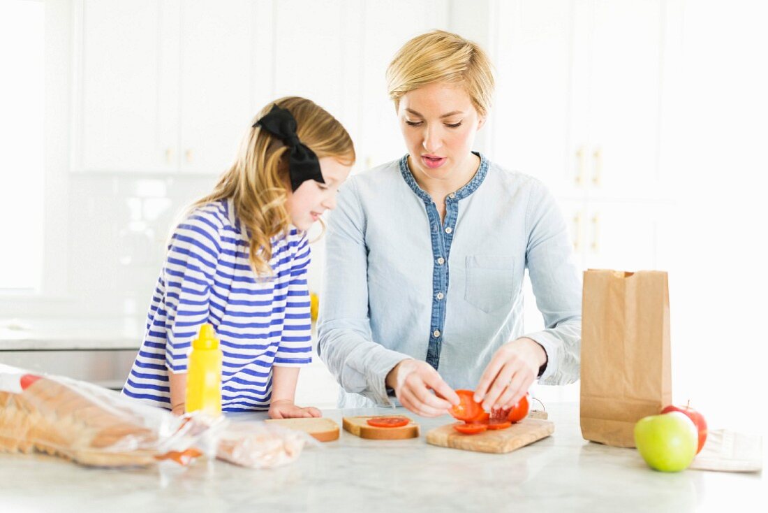 A mother and daughter in a kitchen making sandwiches