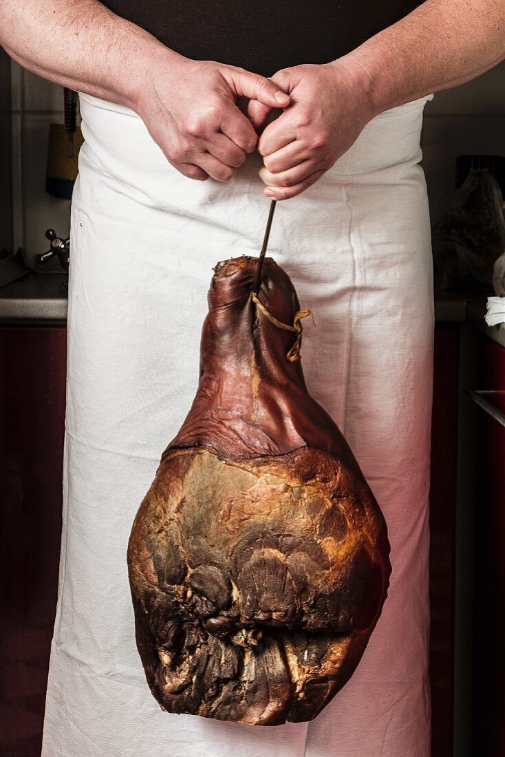 A man holding a large leg of ham