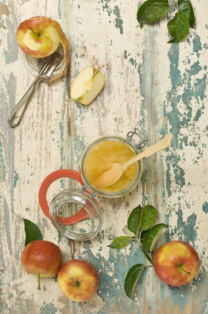 Apfelkompott im Einmachglas daneben frische Äpfel (Aufsicht)