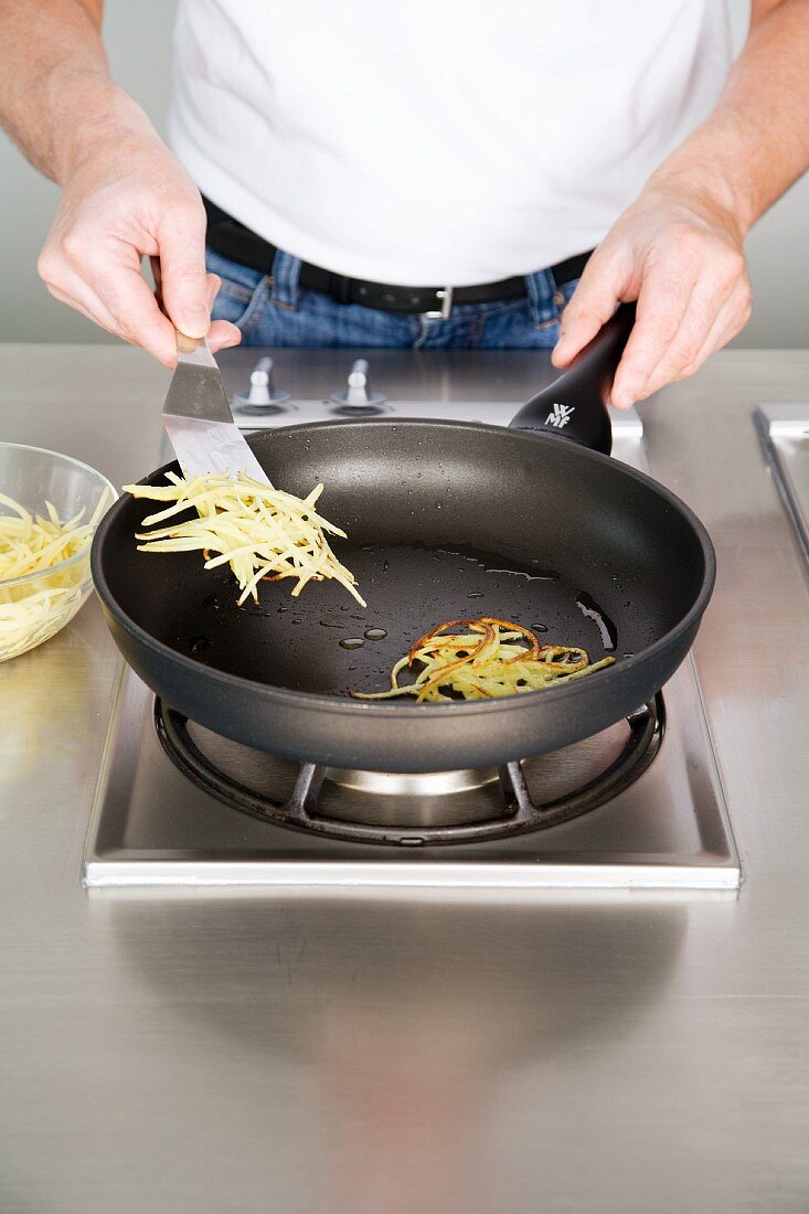 Potato lattice cakes made from grated potato being fried and flipped in a pan