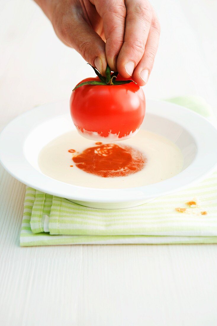 Soup with a stuffed tomato being made