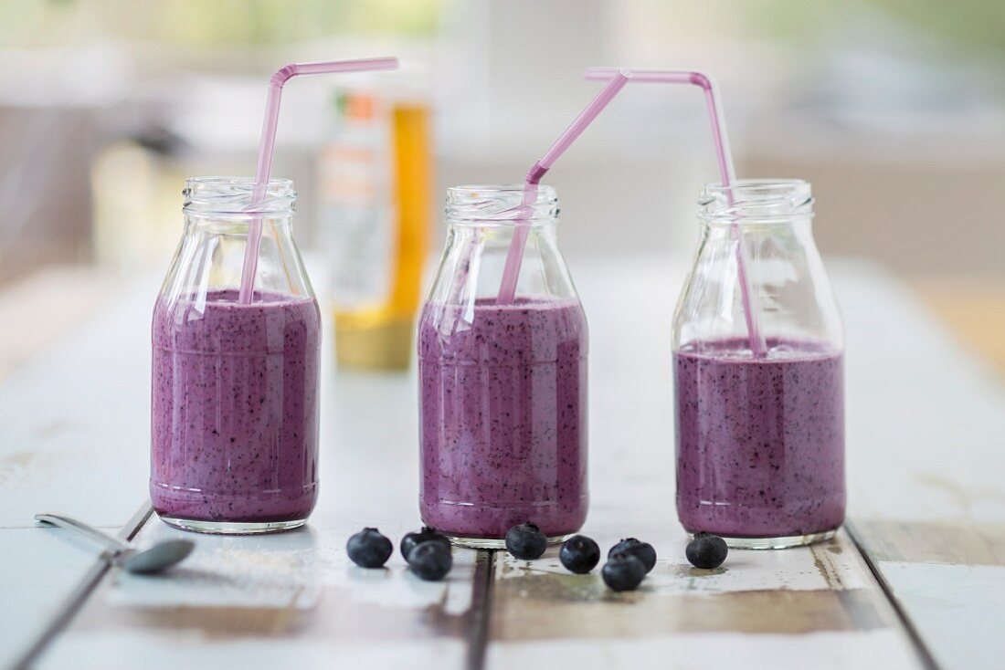 Three bottles of blueberry smoothies with straws