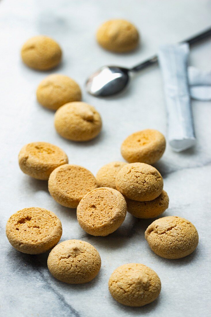 Amaretti and packets of sugar with an espresso spoon on a marble surface