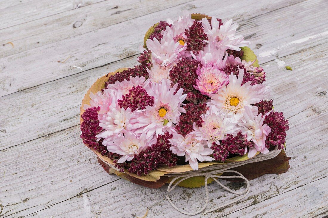 Heart-shaped arrangement of chrysanthemums and autumn leaves