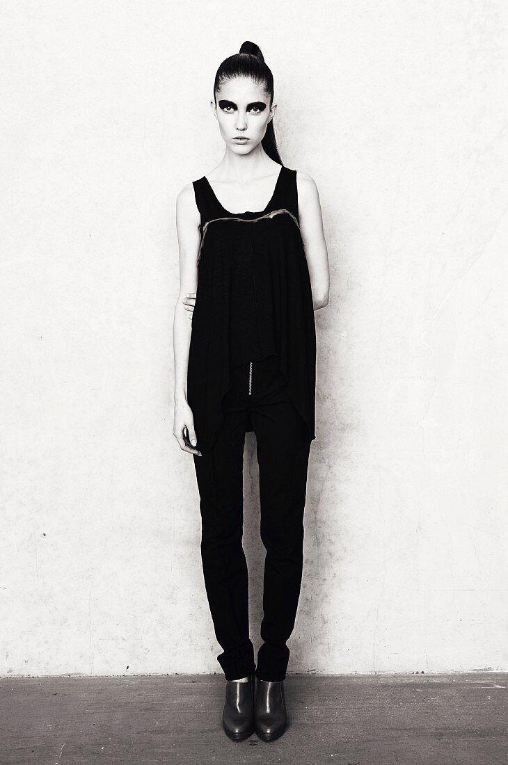 A thin young woman wearing black trousers and a vest top (black and white shot)