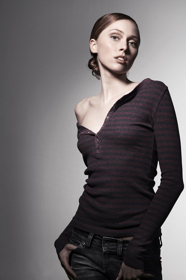 A young woman wearing a knitted top and jeans with one shoulder bare