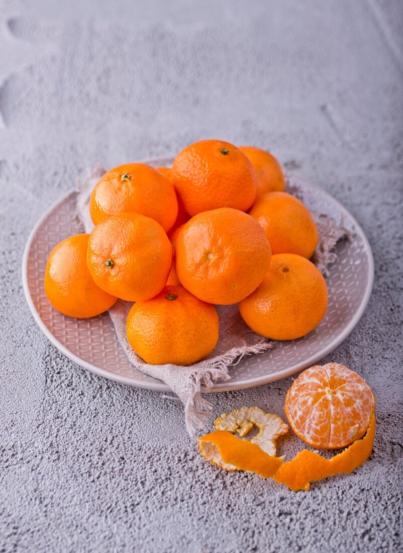 Mandarinen auf Teller, eine davon geschält