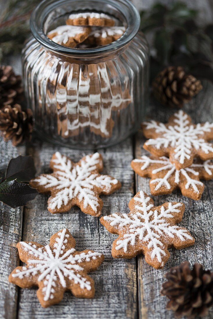 Gingerbread snowflake biscuits decorated with icing, some in a jar