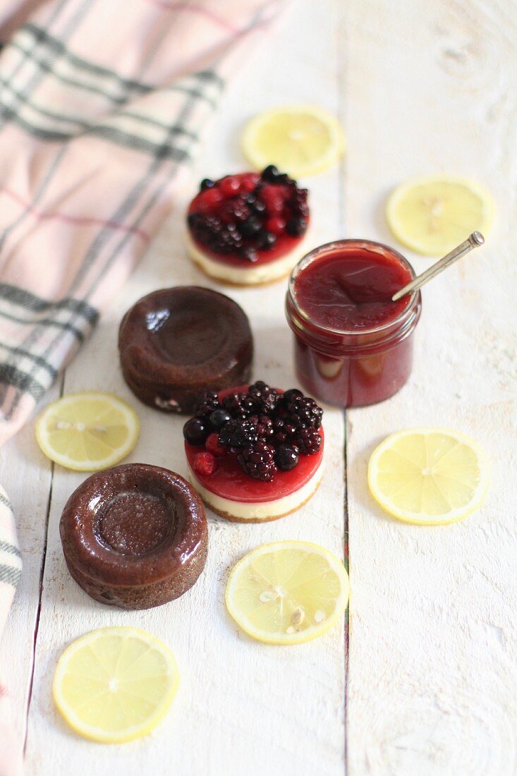 Chocolate cakes, fruits tartlets, a jar of jam and lemon slices
