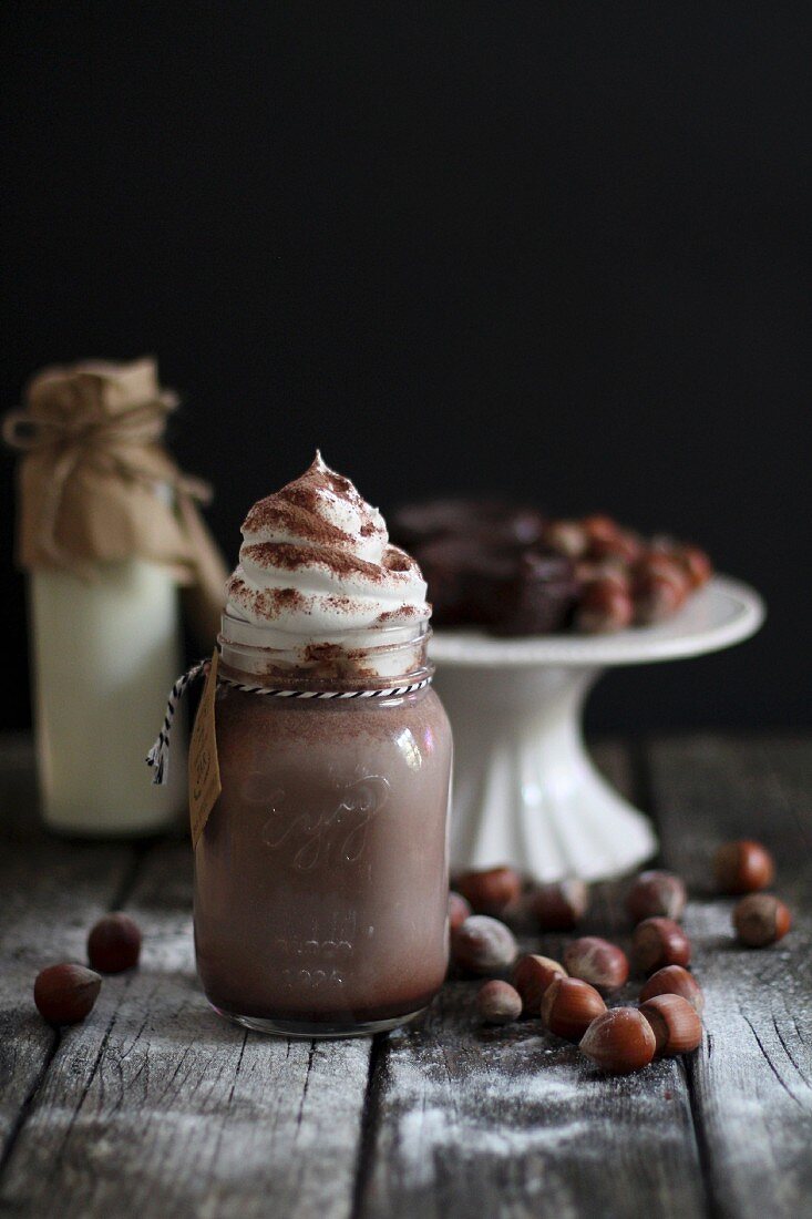 Drinking chocolate topped with cream with hazelnuts and chocolate cake