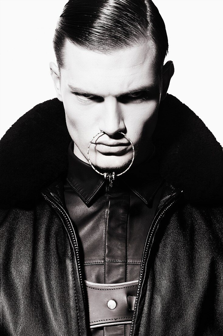 A young man wearing a shirt and a leather jacket with a ring through his nose (black-and-white shot)