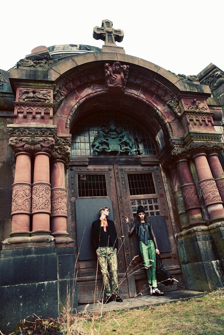 A young couple standing outside the entrance to an old church