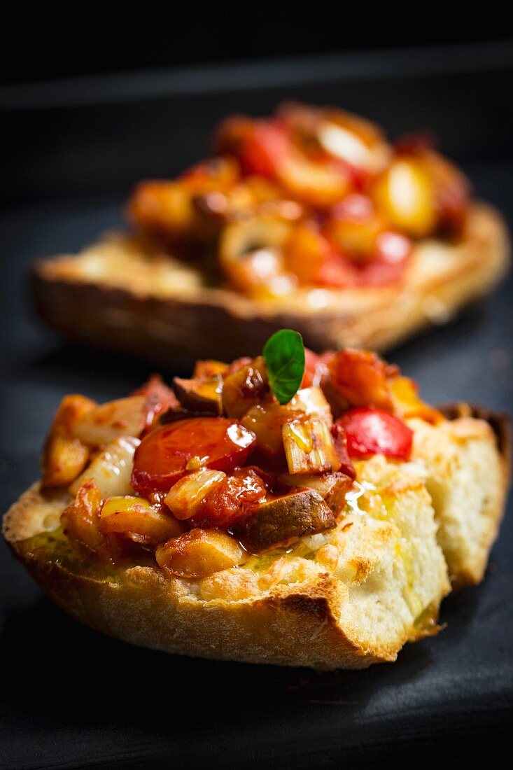 Bruschetta topped with tomatoes and pepper on a black plate