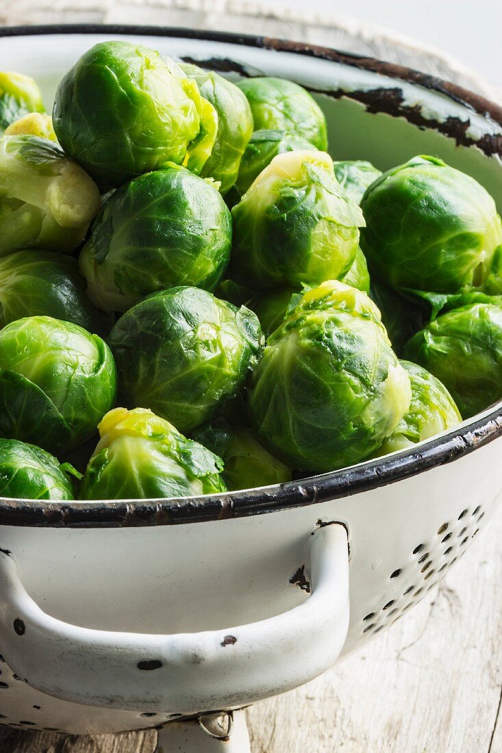 Blanched Brussels sprouts in a white metal colander