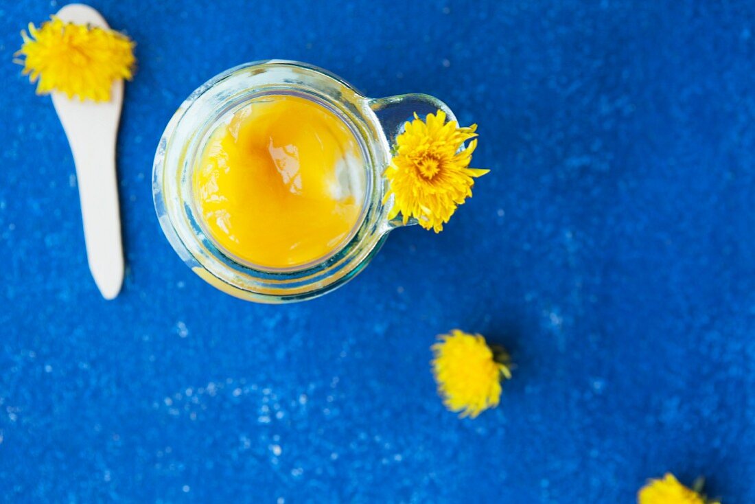 Quark dessert with dandelion sauce in a jar on a blue table