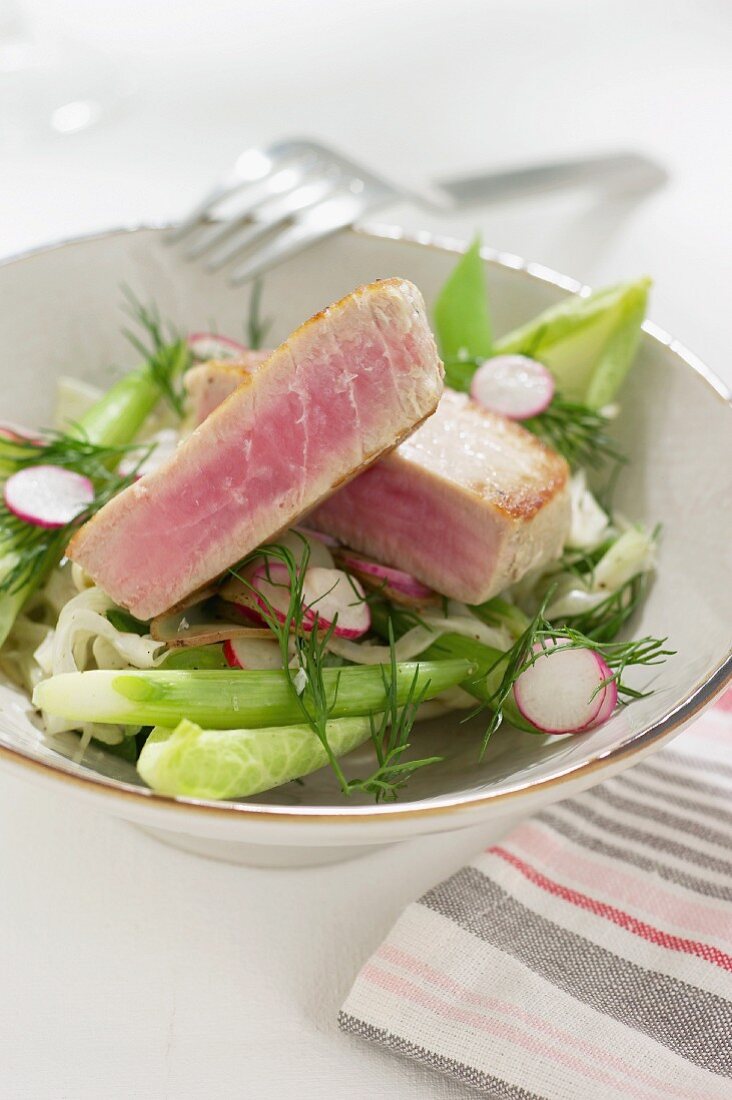 Tuna fish steak on a vegetables salad with radishes and dill