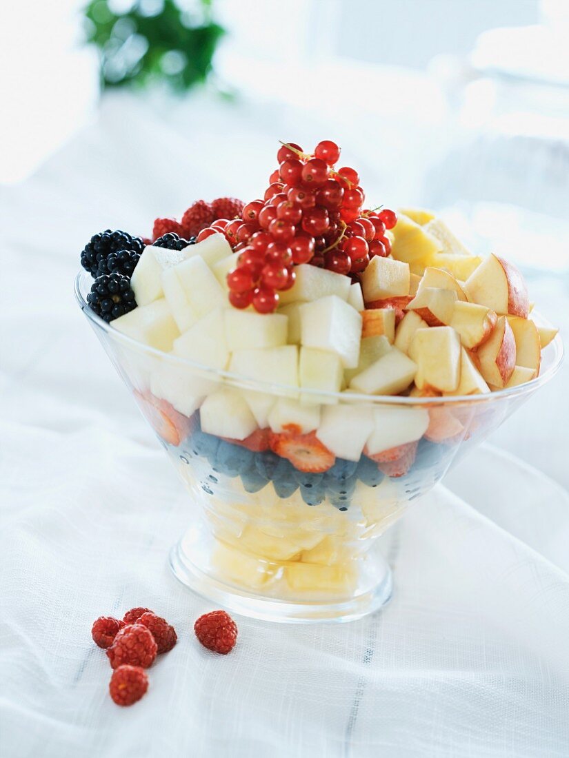 Fruit salad with apples, strawberries, raspberries, pineapple, melon, blueberries and redcurrants