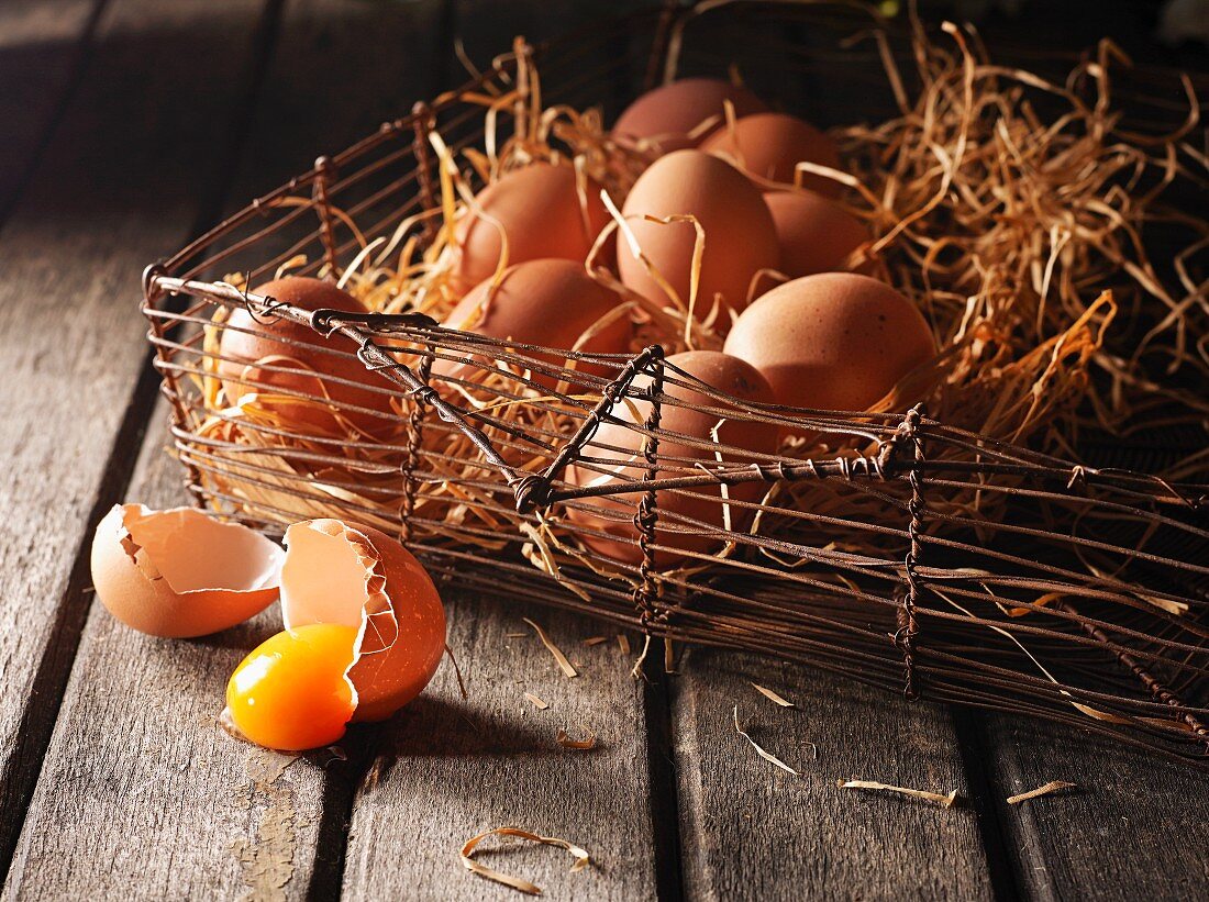 Stillleben mit braunen Eiern in Drahtkorb mit Holzwolle
