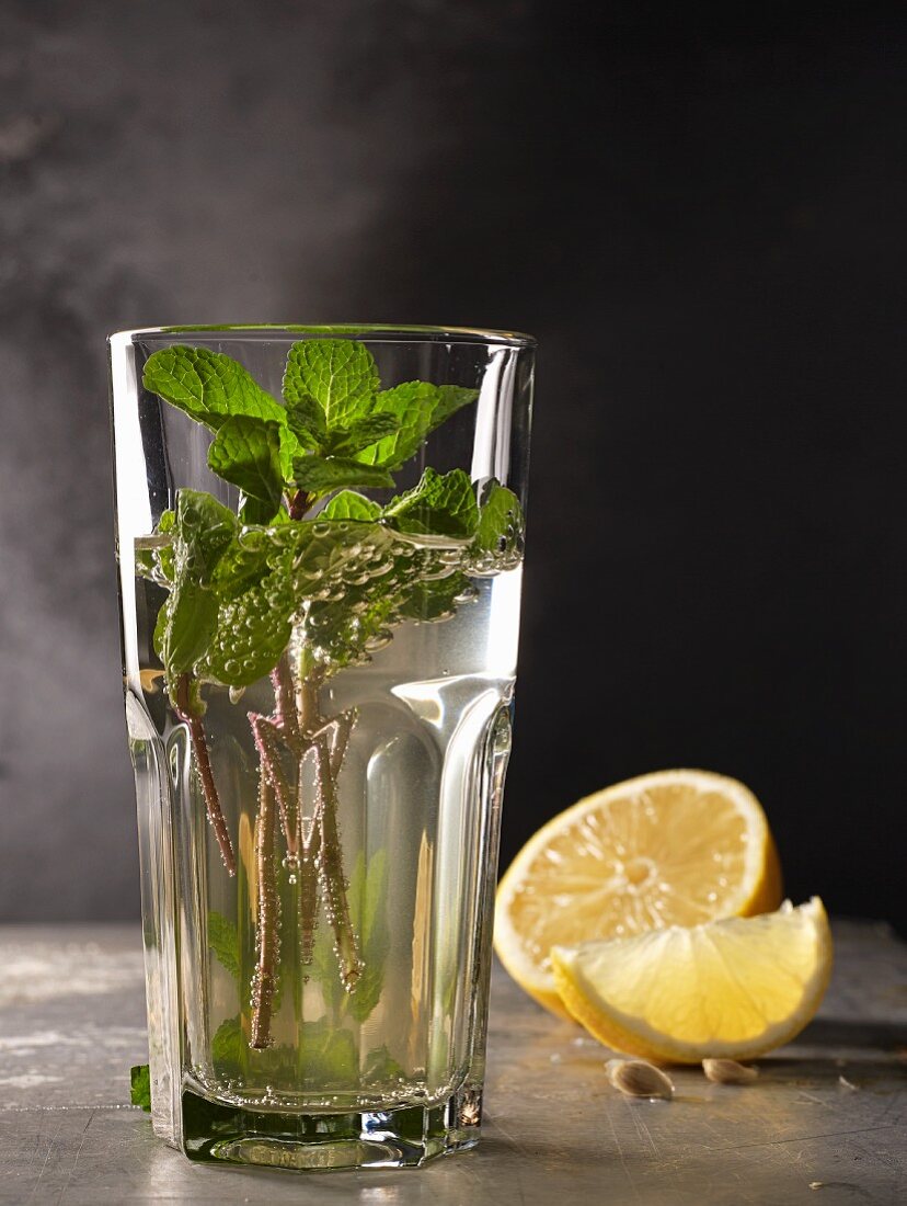 Mint tea in a glass with mint sprigs and lemon