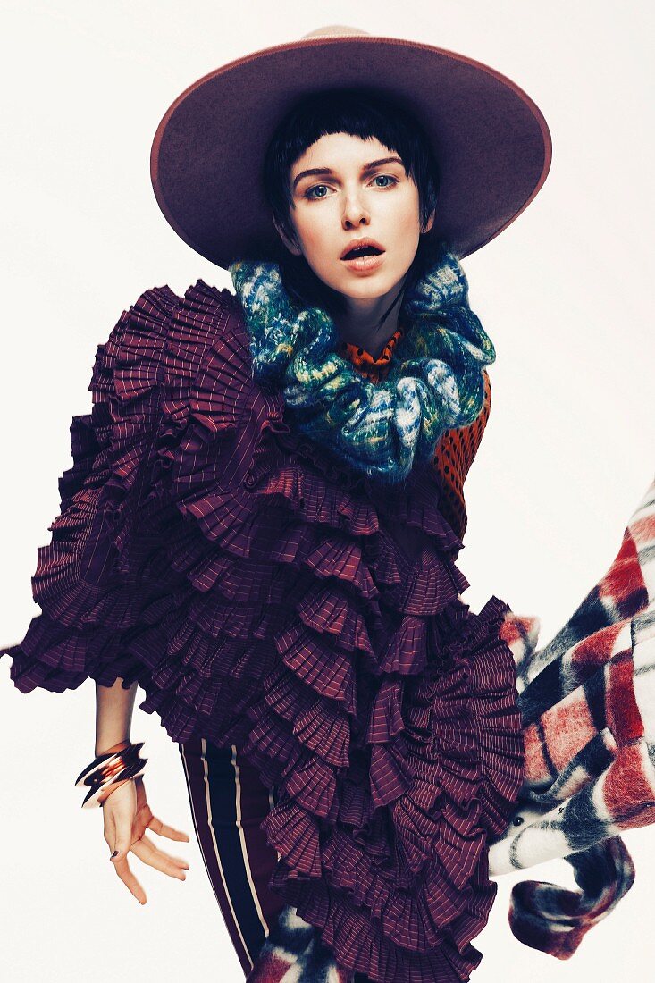 A young woman wearing a ruffled cape and a hat