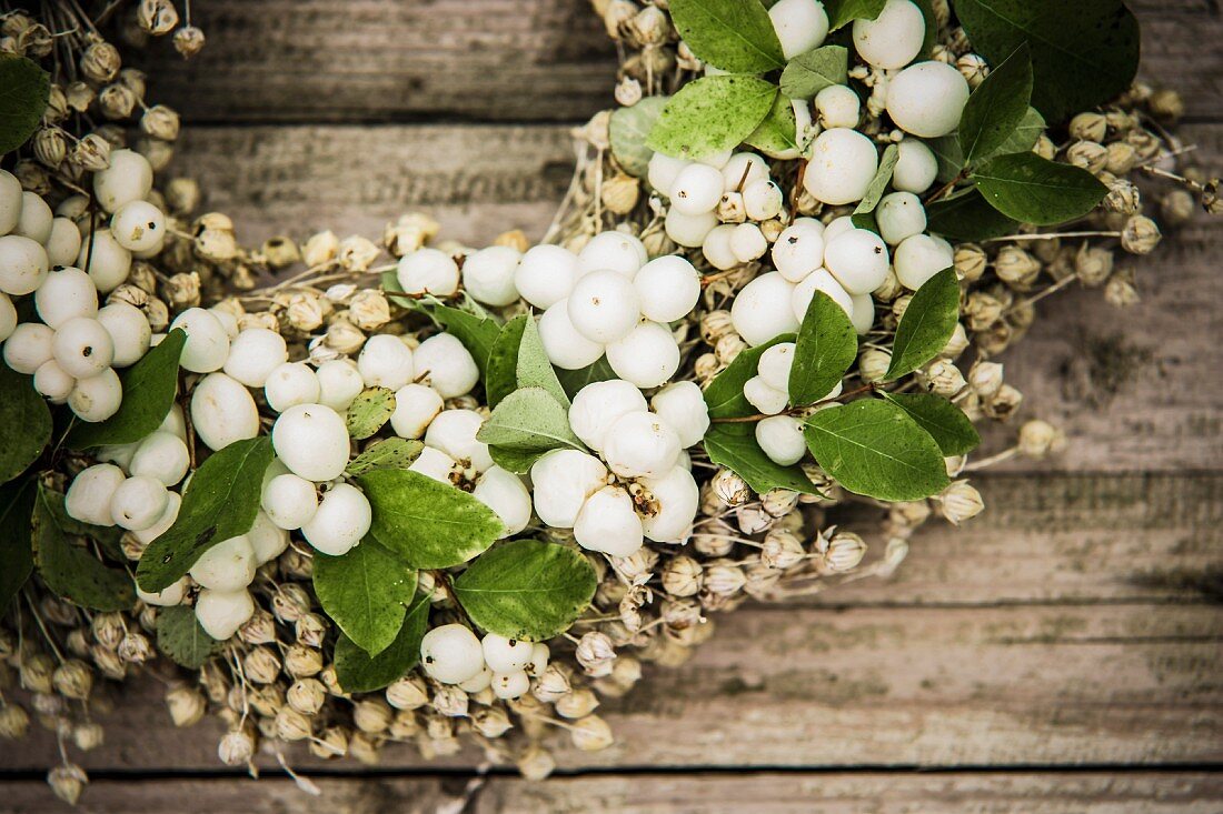 Kranz aus Schneebeeren auf rustikalem Holzuntergrund