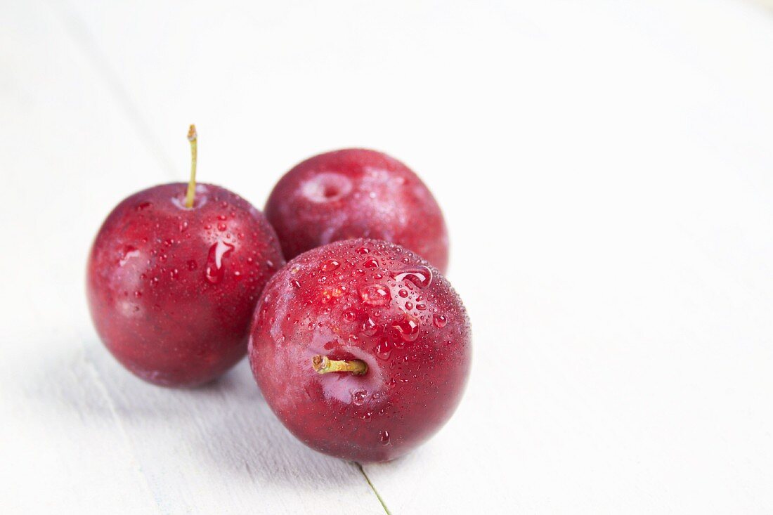 Red plums on a white surface