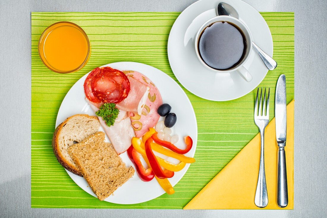Frühstücksgedeck mit Brot, Wurst, Kaffee & Orangensaft (Aufsicht)