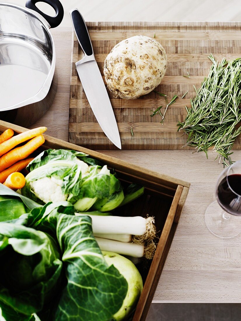 Frisches Gemüse, Rosmarin und Kochutensilien auf Küchenarbeitsplatte
