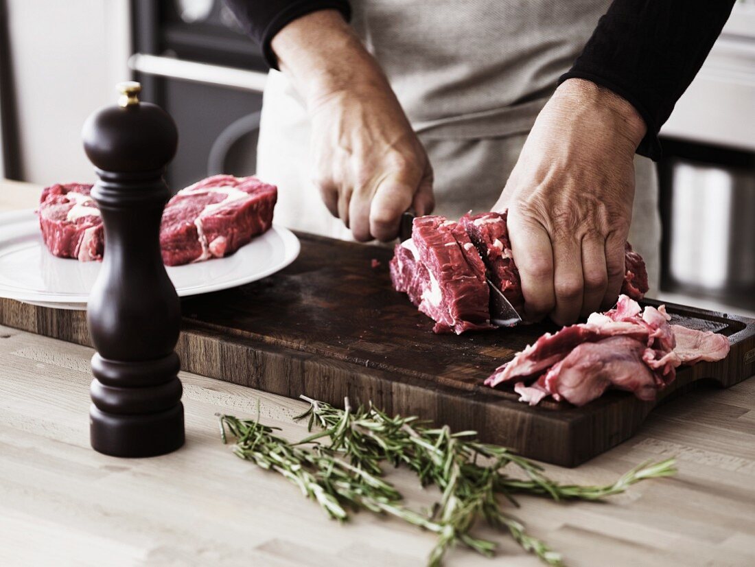 Mann schneidet Rindfleischstück in Steakscheiben