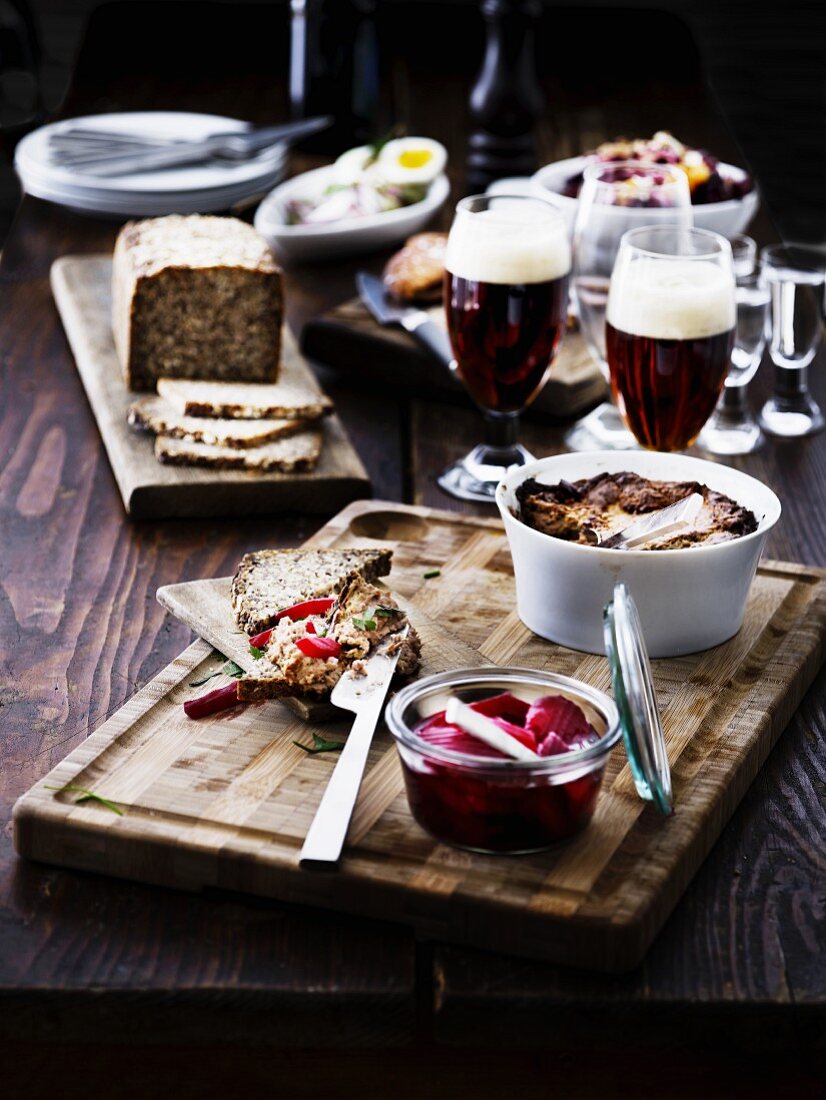 A rustic table laid with bread, pickles and beer