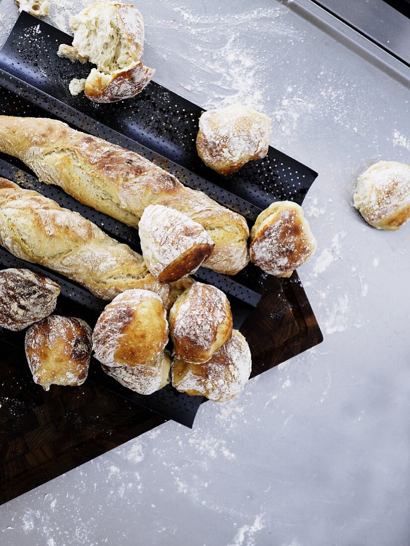 Freshly baked rolls and baguettes on a baguette baking tray