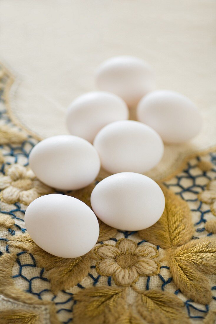 weiße Eier auf bestickter Vintage-Tischdecke mit Blumenmotiv