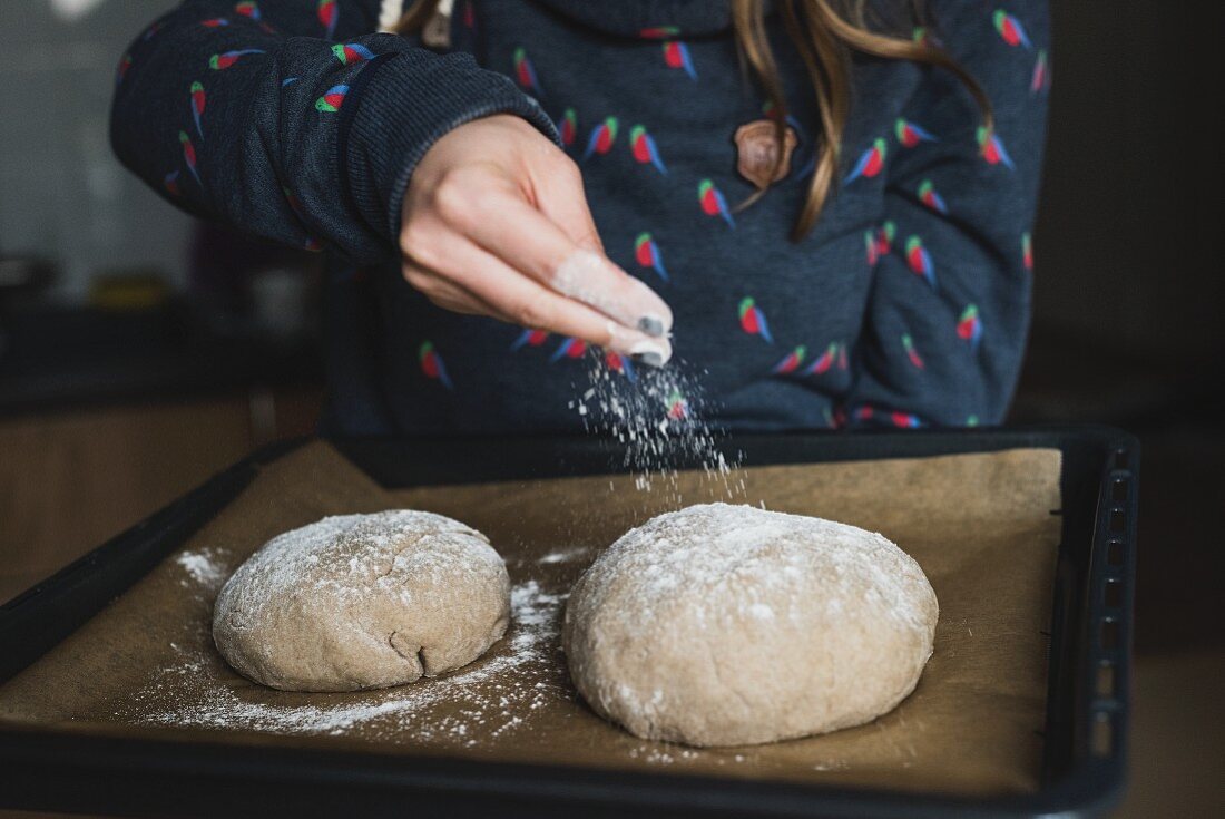 Sour dough bread on a baking tray being dusted with flour