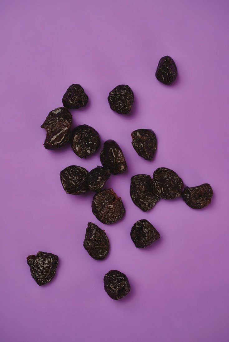 Dried plums on a purple surface (seen from above)