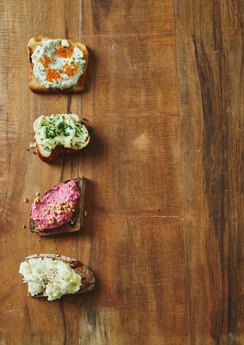 Vier verschiedene Brotaufstriche auf Brotscheiben (Aufsicht)